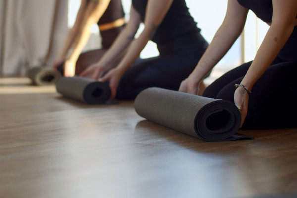 people rolling out yoga mats on a wooden floor